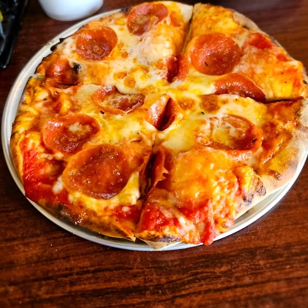 A freshly baked pepperoni pizza, sliced and served on a metal tray at Reifschneiders Grill and Grape.