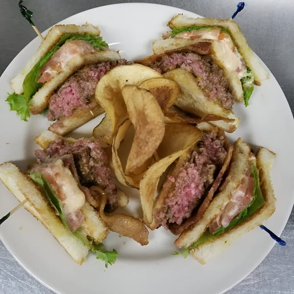 A Reifschneiders Grill and Grape burger club sandwich, cut into quarters, with house-made potato chips.